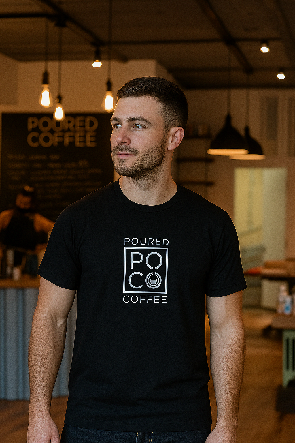 Man wearing a black Poured Coffee organic cotton t-shirt inside a modern coffee shop.